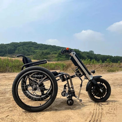 Izdelek na sliki je električni priklop za invalidski voziček, model Mijo MT01. Na sliki je prikazan električni priklop, ki se povezuje z invalidskim vozičkom, kar omogoča lažje premikanje. Priklop ima dva velika kolesa in en manjši kolesec, kar omogoča stabilnost in manevriranje. V ozadju je naravna pokrajina z zelenjem in modrim nebom.