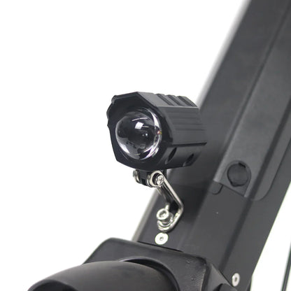 Izdelek je električni priklop, model Mijo MT01. Na sliki je prikazan del električnega skiroja z nameščeno lučko, ki je zasnovana za izboljšanje vidnosti med vožnjo. Lučka je črne barve in je pritrjena na okvir skiroja, kar nakazuje na funkcionalnost in praktičnost pri nočni vožnji.