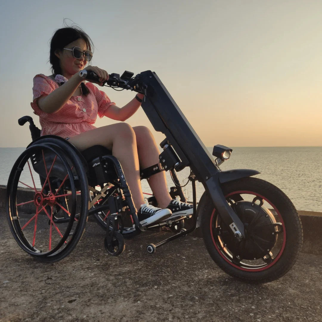 Izdelek je električni priklop za invalidski voziček, model Mijo MT01. Na sliki je vidna oseba, ki uporablja ta priklop, ki omogoča enostavno premikanje. Priklop je zasnovan za izboljšanje mobilnosti in udobja uporabnikov invalidskih vozičkov, kar je razvidno iz njegove konstrukcije in dizajna. Ozadje prikazuje mirno vodno površino ob sončnem zahodu.