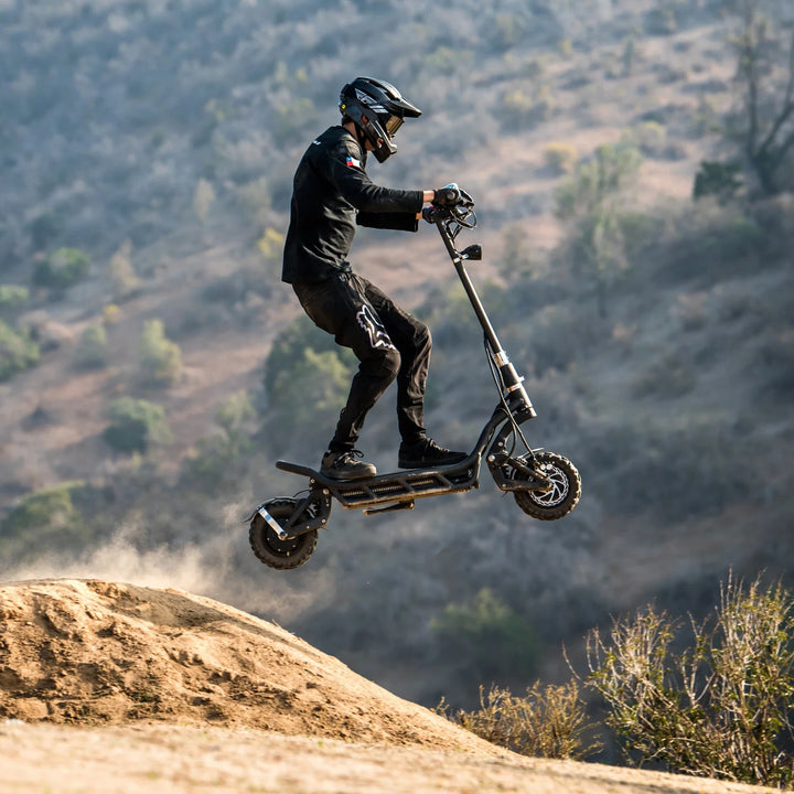 Electric Scooter Nami Burn E 3 Max, performing an impressive jump over rugged terrain, showcasing its power.
