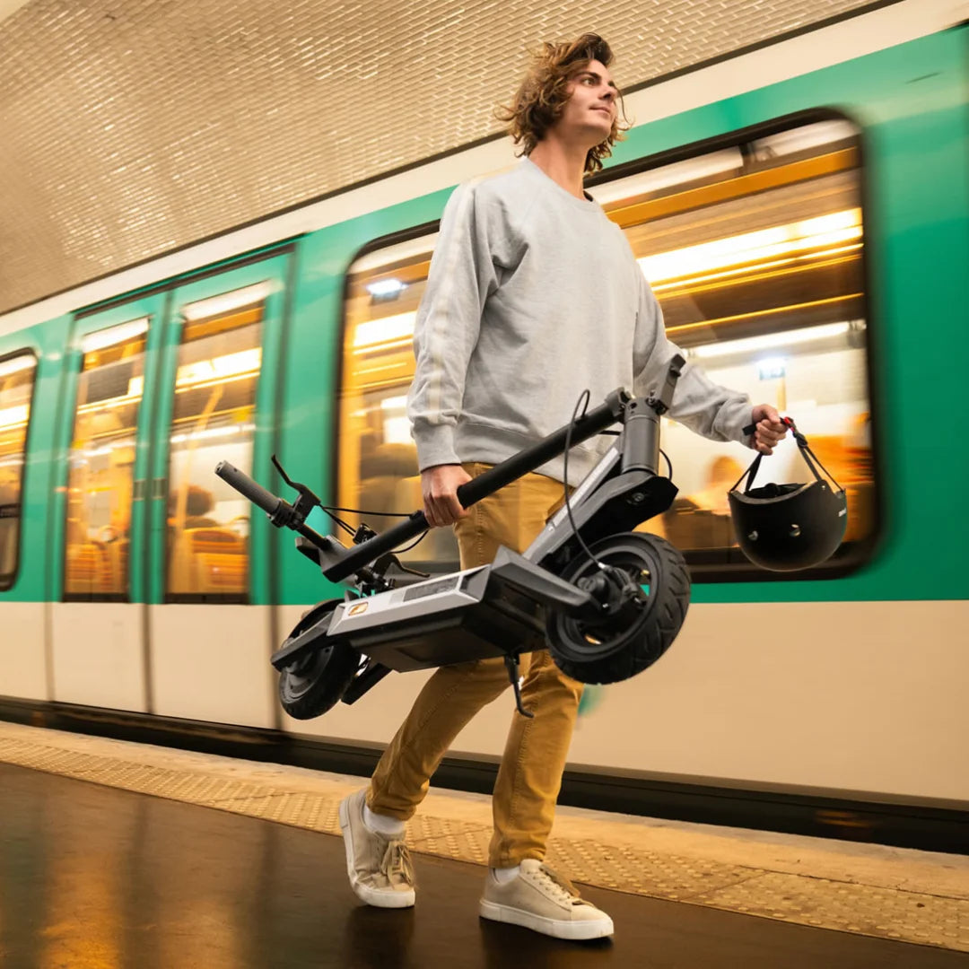 Oseba nosi električni skiro Navee S40 med hojo na postaji podzemne železnice.