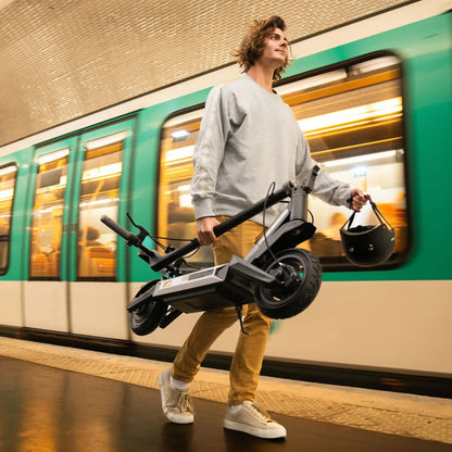 Oseba nosi električni skiro Navee S40 med hojo na postaji podzemne železnice.