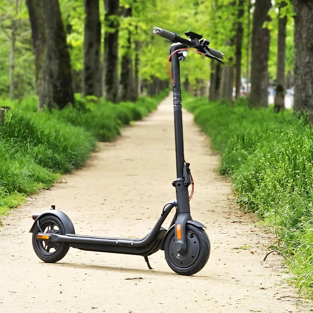 Eleganten električni skiro Navee V25i Pro parkiran na poti, obdani z drevesi.