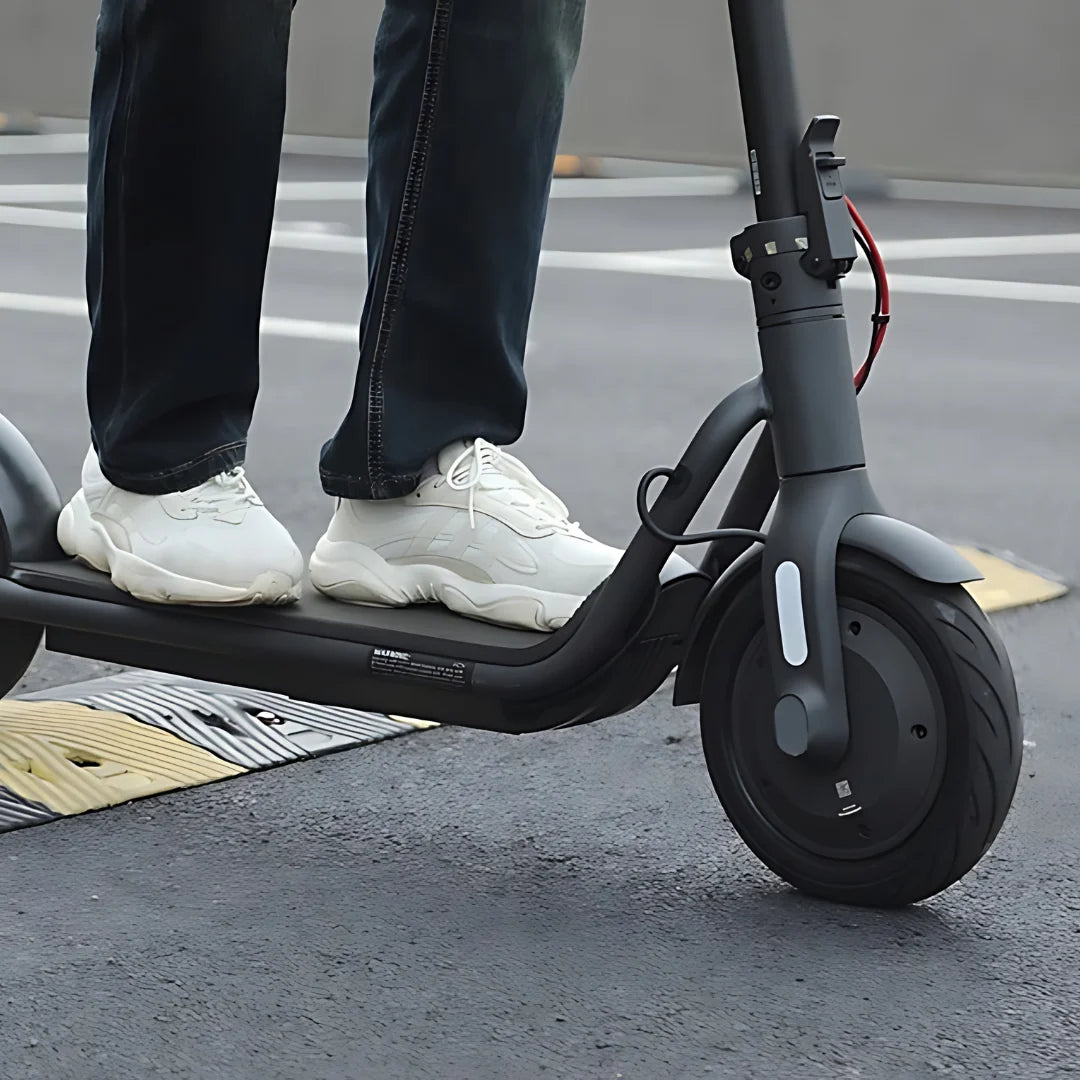 Oseba stoji na električnem skiroju Navee V40i Pro na pločniku.