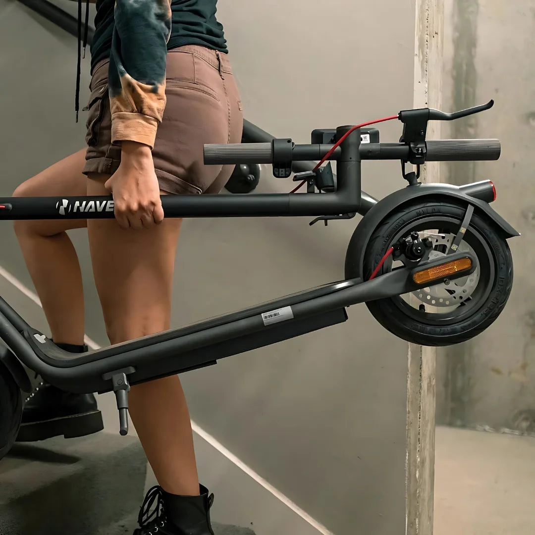 Oseba nosi električni skiro Navee V50i Pro po stopnicah.