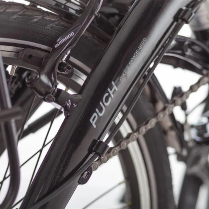 Od blizu posnet črn okvir električnega kolesa Puch H 1 1 z vidno verigo in komponentami Shimano.