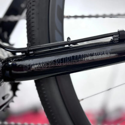 Izdelek je električno kolo, znamke Raymon, model GravelRay E 7.0. Na sliki je del okvirja kolesa, ki je črne barve, z vidnimi detajli, kot so kabli in zobniki. Oprema kaže na kakovostno izdelavo, kar je značilno za to znamko. Kolo je namenjeno vožnji po gravel površinah in nudi dobro zmogljivost.