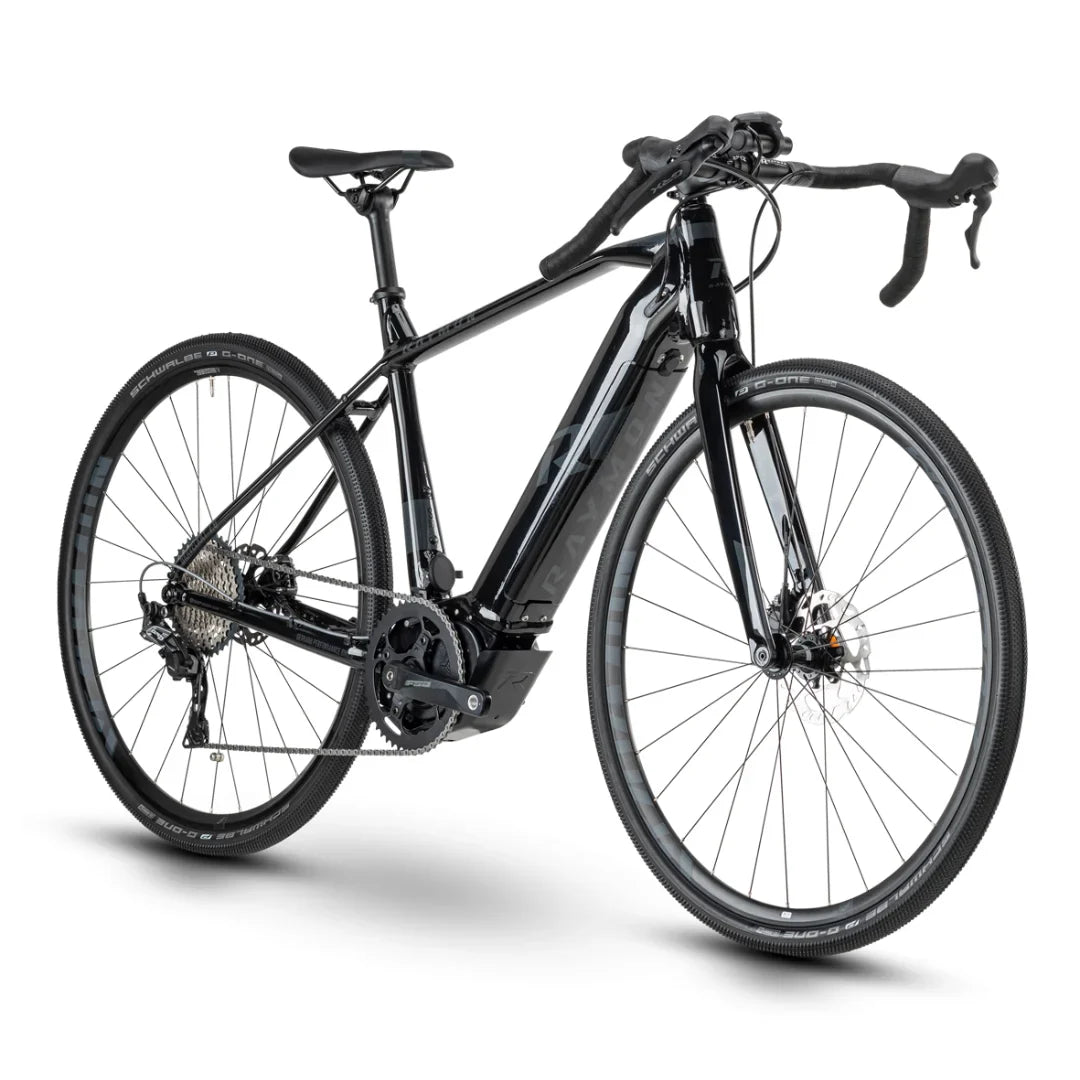 Izdelek na sliki je električno kolo, znamke Raymon, model GravelRay E-7.0. Kolo ima športno zasnovo z ozkimi kolesi, kar ga naredi primernega za gravel in cestno vožnjo. Vidni so tudi hidravlični disk zavore ter električni motor, kar nakazuje na njegovo zmogljivost in udobje med vožnjo. Barvna kombinacija je elegantna, pretežno črna s svetlejšimi detajli.