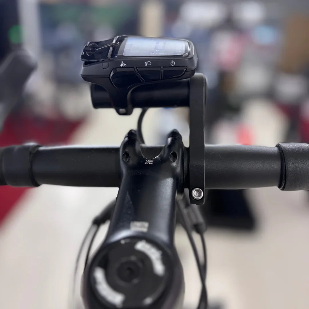 Izdelek je električno kolo znamke Raymon, model GravelRay E 7.0. Na sliki je vidna krmilo kolesa s pritrjenim zaslonom, ki prikazuje različne funkcije, kot so način vožnje in svetloba. Kolo ima robustno zasnovo, kar je značilno za gravel kolesa, kar omogoča vožnjo po različnih terenih.