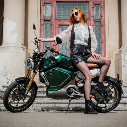 Model pozira na električnem skuterju Super Soco TC in prikazuje njegovo elegantno obliko.