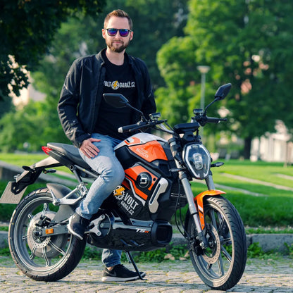 Moški sedi na električnem skuterju Super Soco Tsx v parku.