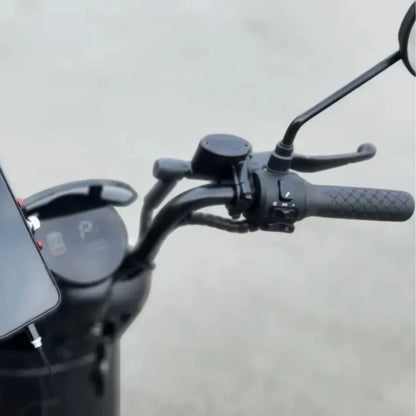 Na sliki je električna motorna kolesa, model "Stromko". Prikazana je krmna enota z ročajem, na katerem je nameščen tudi telefon. Vidni so različni nadzorni elementi, vključno z ogledalom in gumbom za upravljanje. Zasnova je moderna in minimalistična, kar je značilno za električna vozila.