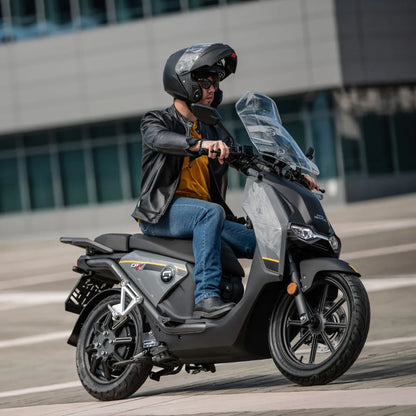 Voznik s čelado na električnem skuterju Super Soco Cpx v urbanem okolju.