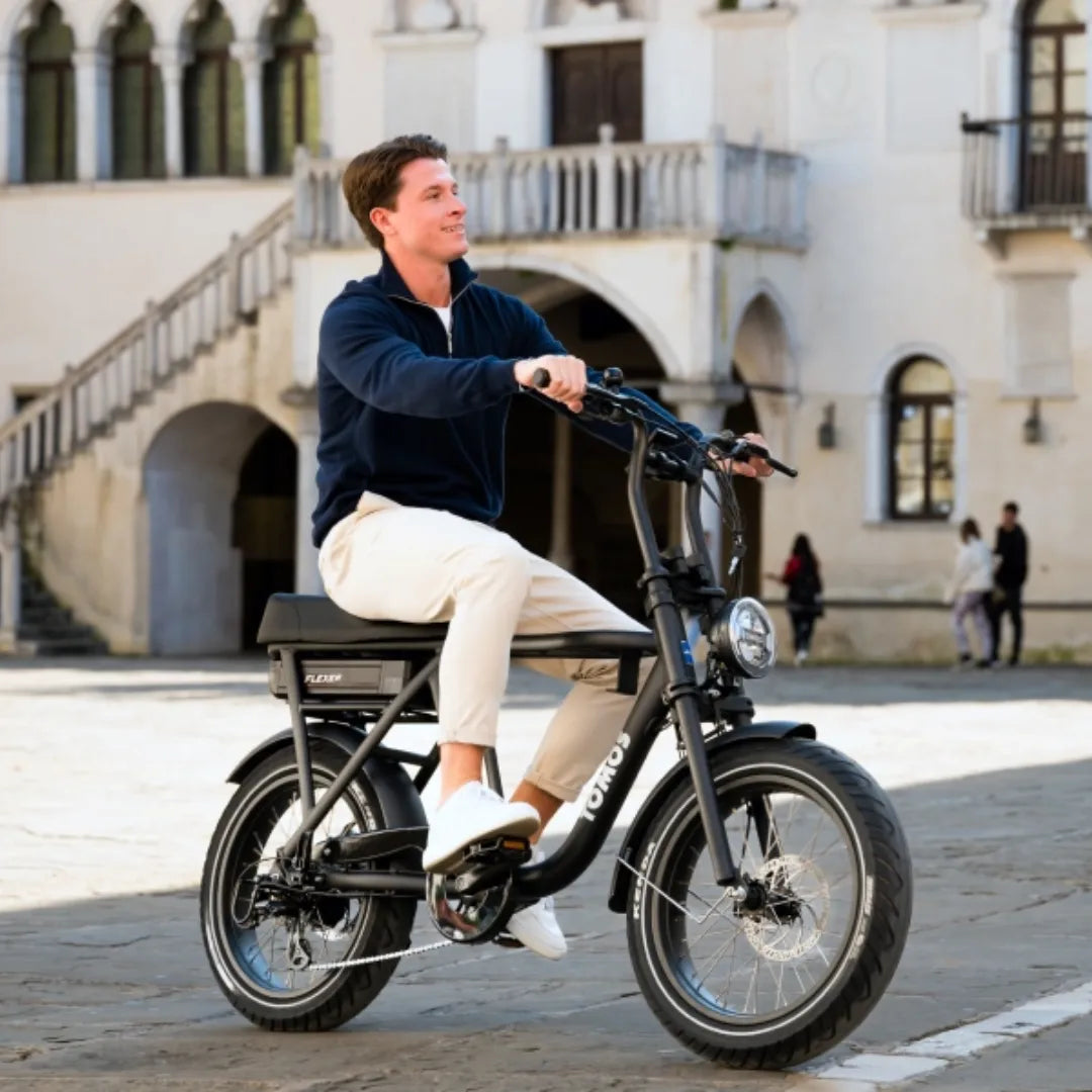 Moški se vozi z električnim kolesom Tomos Flexer v slikovitem urbanem okolju.
