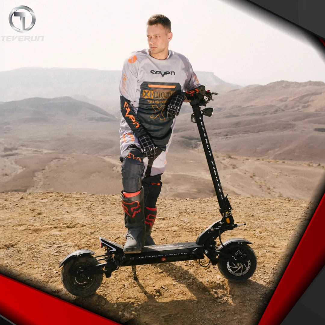 Voznik stoji na električnem skiroju Teverun Fighter 11 Plus v puščavski pokrajini.