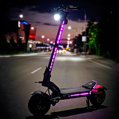 Električni skiro Teverun Fighter 11 Plus parkiran na ulici, osvetljen z živahnimi lučmi v mraku.