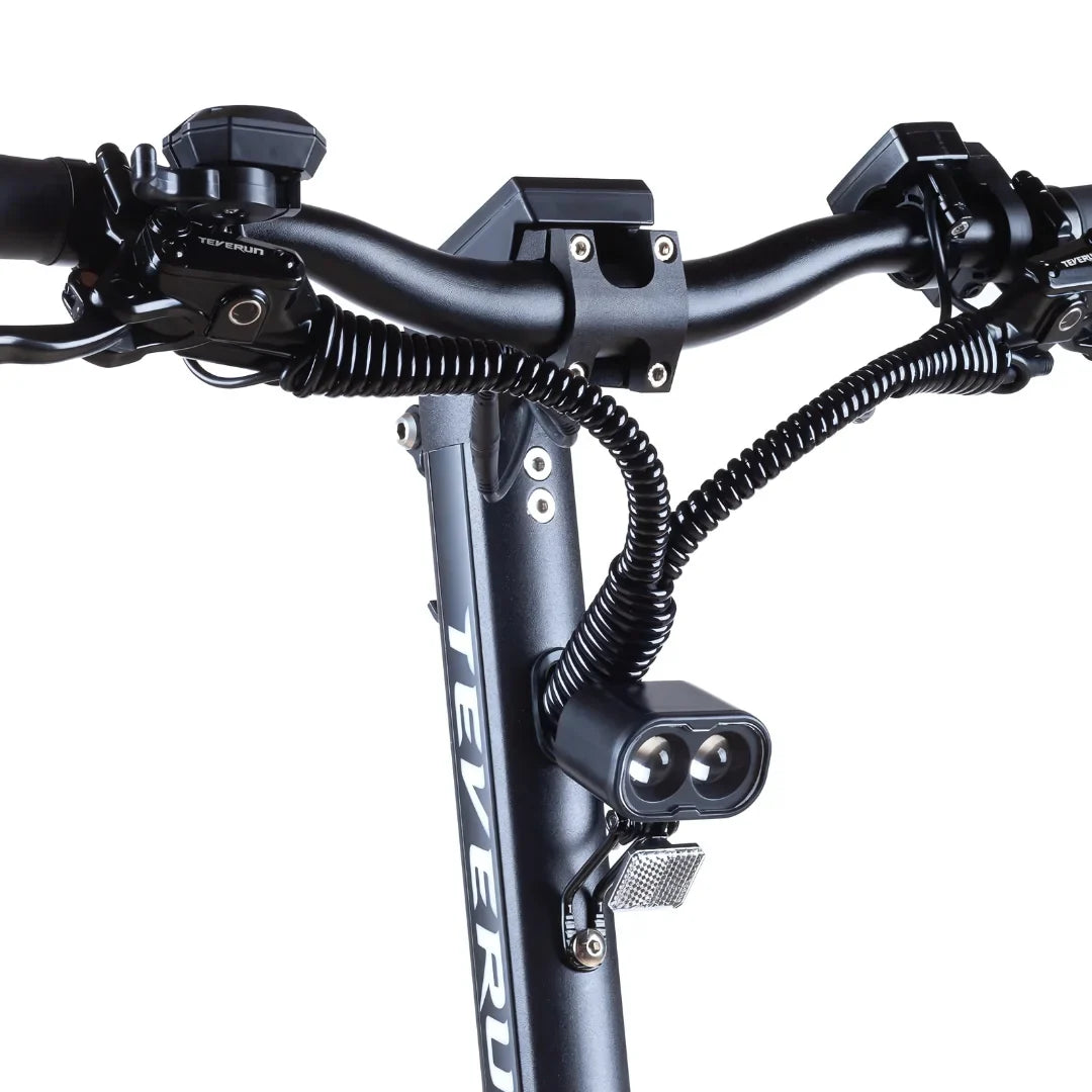 Izdelek na sliki je električni skiro, model Teverun Fighter Mini Pro 2025. Na sliki so vidni krmilo skiroja, z različnimi kontrolniki in lučmi. Opremljen je z dvema svetlobama za boljšo vidljivost ter ergonomskimi ročaji, kar omogoča udobno vožnjo. Zasnova je moderna in robustna, kar nakazuje na visoko kakovost in zmogljivost.