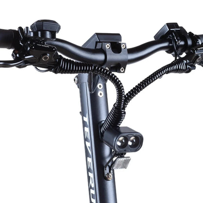 Izdelek na sliki je električni skiro, model Teverun Fighter Mini Pro 2025. Na sliki so vidni krmilo skiroja, z različnimi kontrolniki in lučmi. Opremljen je z dvema svetlobama za boljšo vidljivost ter ergonomskimi ročaji, kar omogoča udobno vožnjo. Zasnova je moderna in robustna, kar nakazuje na visoko kakovost in zmogljivost.