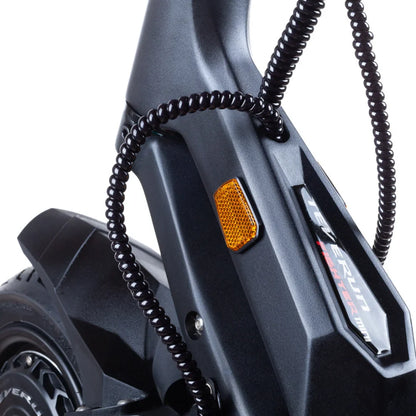 Izdelek je električni skiro, znamke Teverun, model Fighter Mini Pro 2025. Na sliki je vidna podrobnost skiroja, kjer je prikazana struktura okvirja, reflektor v oranžni barvi ter zaščitna cev za kable. Barva skiroja je temna, kar mu daje sodoben in robusten videz.