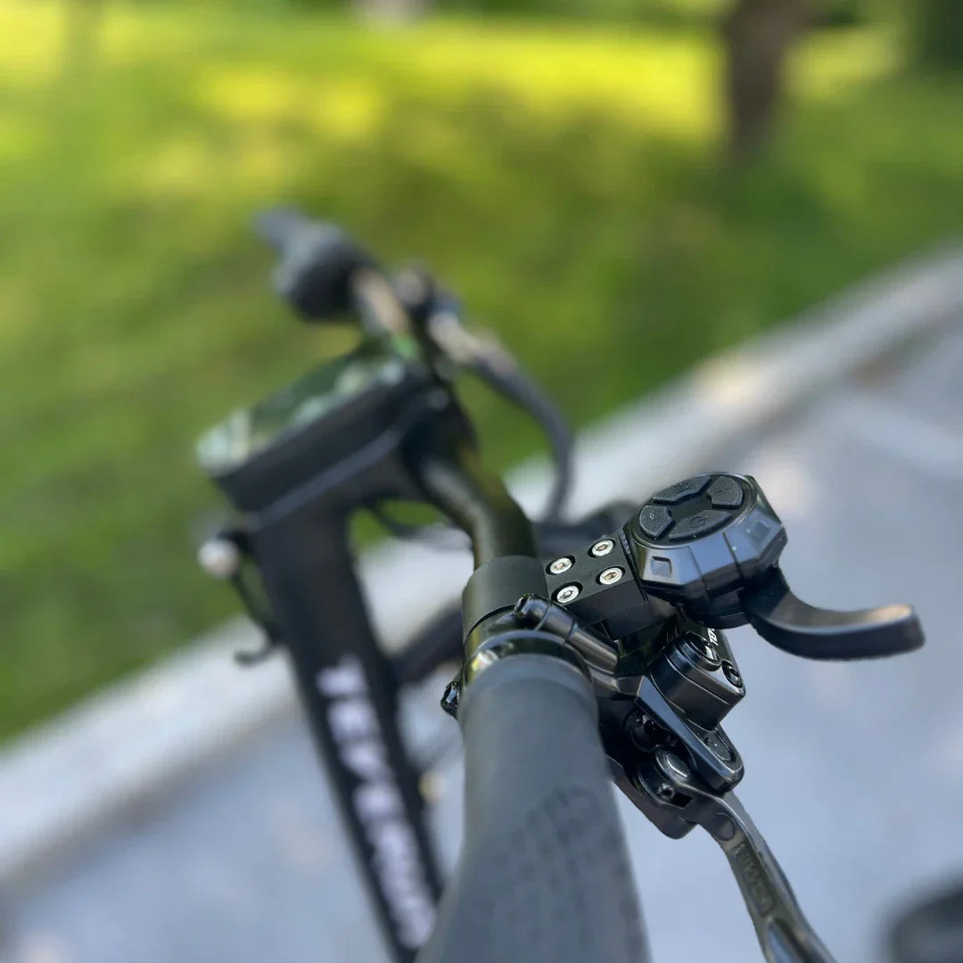 Izdelek je električni skiro, model Teverun Fighter Mini Pro iz leta 2025. Na sliki je prikazan del krmila skiroja, kjer so vidni ročaji in nadzorna plošča. Oprema se zdi robustna in omogoča enostavno upravljanje, kar je značilno za električne skiroje. V ozadju je zeleno okolje, kar nakazuje na uporabo skiroja na prostem.