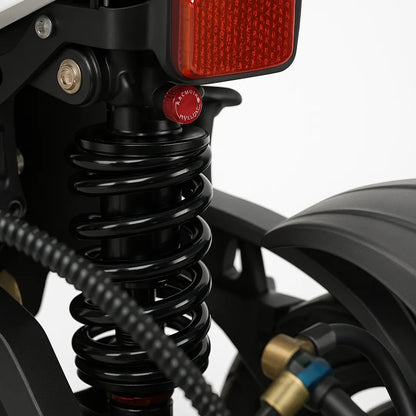 Izdelek je električni skiro, model Teverun Fighter Supreme 7260 Ultra. Na sliki je prikazan del zadnjega vzmetenja skiroja, vključno z vzmetjo in nekaterimi komponentami, kot so cevke in povezave. Vidna je tudi rdeča lučka, ki služi kot zadnje svetlo. Vse komponente so zasnovane za zagotavljanje udobne vožnje in stabilnosti.