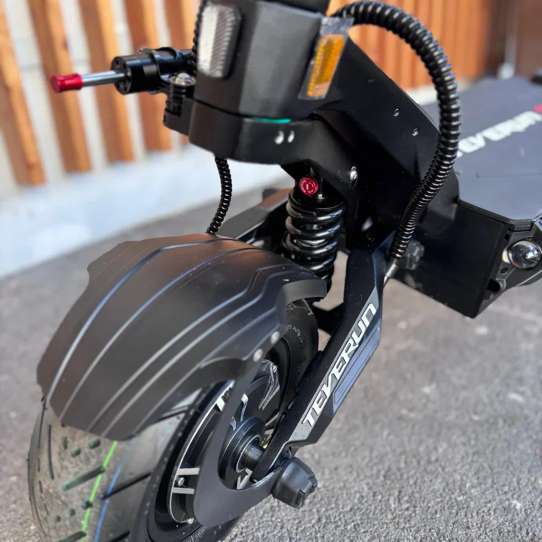 Izdelek je električni skiro, znamke Teverun, model Fighter Supreme 7260 Ultra. Na sliki je prikazan sprednji del skiroja, kjer so vidni robusten kolesni mehanizem, vzmetenje ter delovni elementi, kot so luči in ročica za zaviranje. Materiali izgledajo trpežno, kar nakazuje na kakovostno izdelavo in zmogljivost skiroja.