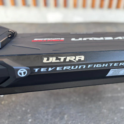 Izdelek je električni skiro, znamke Teverun, model Fighter Supreme 7260 Ultra. Na sliki je vidna stranska površina skiroja, kjer so jasno označeni imeni modela in znamke. Površina je temno obarvana, z modernim dizajnom in teksturo, ki daje občutek trpežnosti.