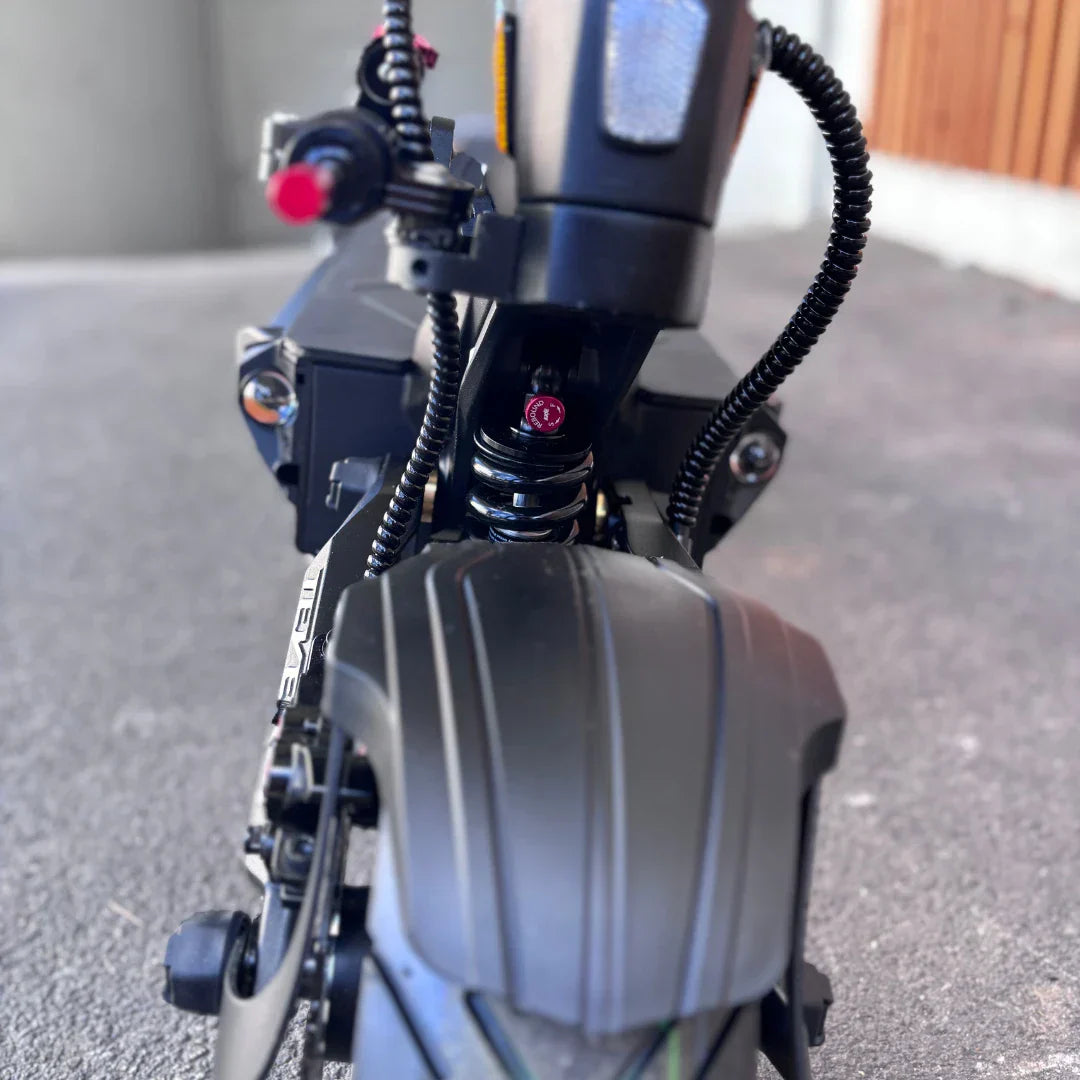 Izdelek je električni skiro, znamke Teverun, model Fighter Supreme 7260 Ultra. Na sliki je vidna sprednja stran skiroja, kjer so prikazani vzmetni sistem in del kolesa. V ozadju se vidi tudi del okvirja ter kabli, kar nakazuje na napreden sistem in robustno zasnovo skiroja.