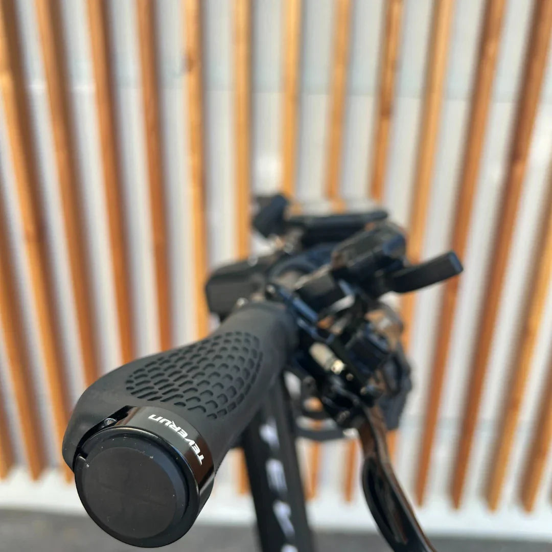 Izdelek je električni skiro, znamke Teverun, model Fighter Supreme 7260 Ultra. Na sliki je vidna ročica skiroja z ergonomskim oprijemom ter različni kontrolni elementi, ki omogočajo upravljanje naprave. V ozadju so vidne lesene letvice, kar ustvarja kontrast s črno barvo skiroja.