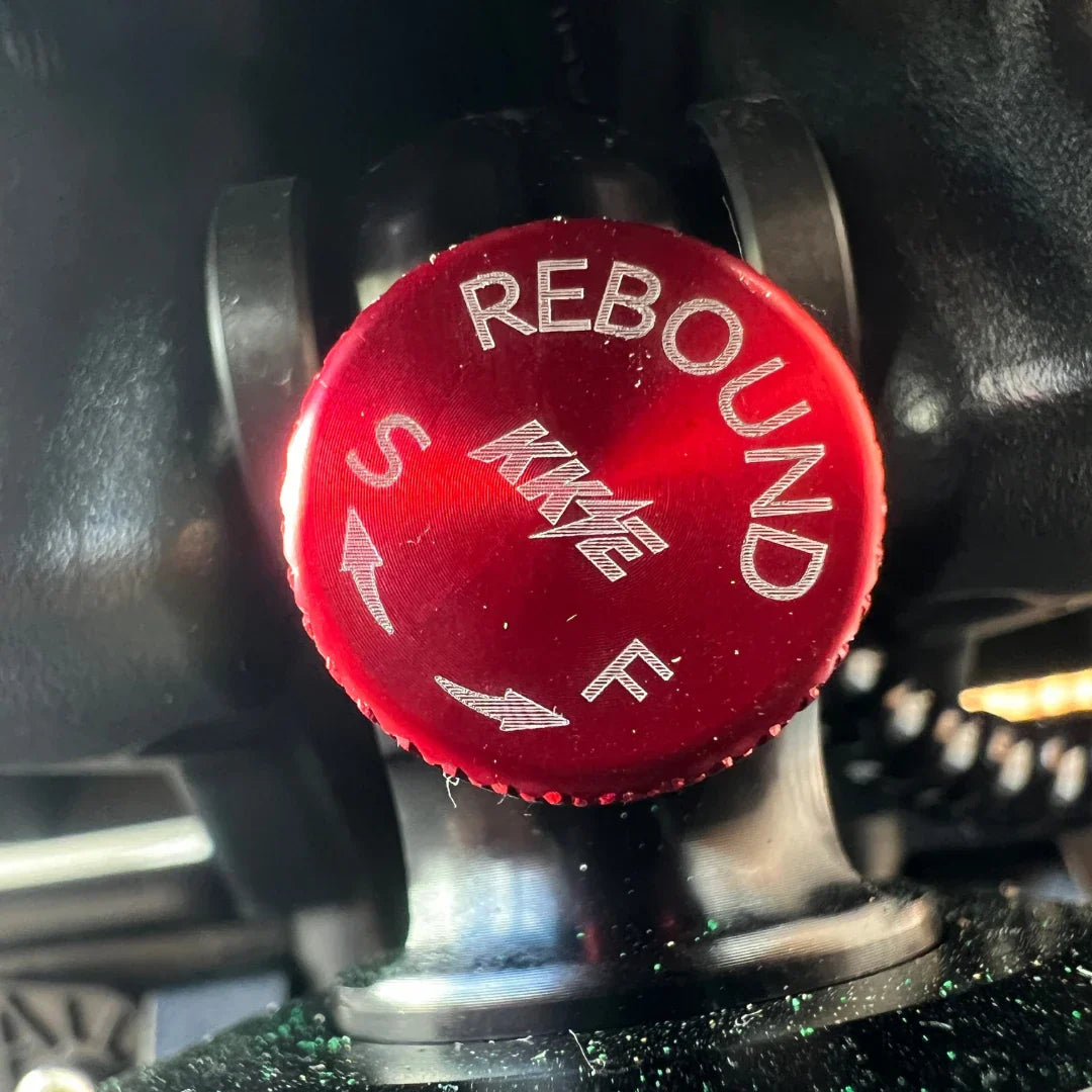 Izdelek je električni skiro, model Teverun Fighter Supreme 7260 Ultra. Na sliki je vidna rdeča nastavitvena gumb za povratno delovanje (rebound), ki omogoča prilagajanje vzmetenja. Gumb je označen z oznakama "S" in "F", kar verjetno pomeni nastavitve za mehkejše ali trše delovanje. Ozadje je temno, kar poudarja detajle gumbov.