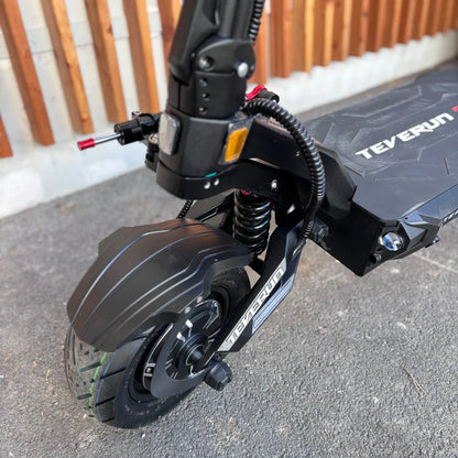 Izdelek na sliki je električni skiro, znamke Teverun, model Fighter Supreme 7260 Ultra. Na sliki je prikazan del skiroja, vključno z zadnjim kolesom, vzmetenjem in delom krmila. Opremljen je z robustnim kolesom in sistemom za vzmetenje, kar nakazuje na dobro zmogljivost in udobje pri vožnji.