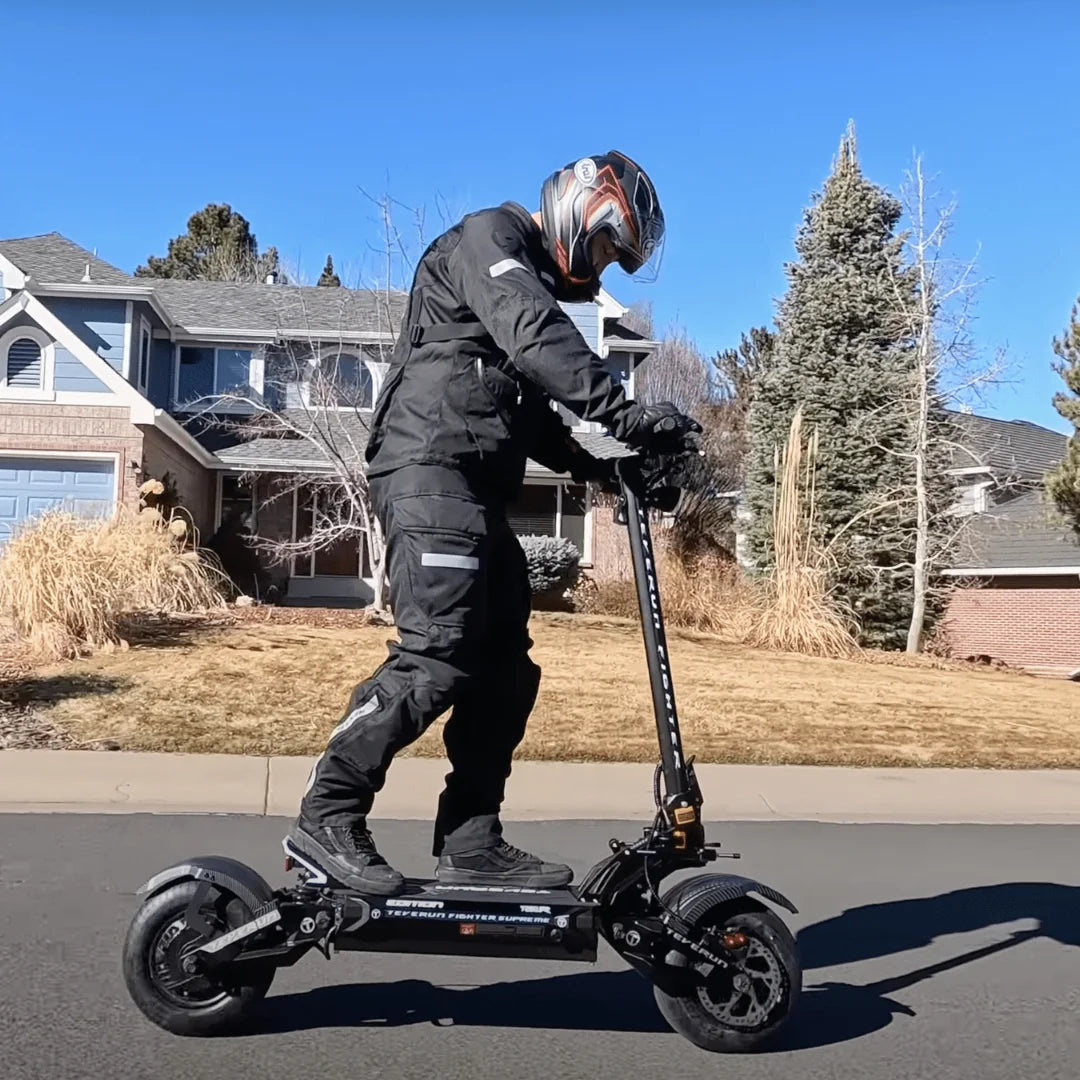 Voznik v opremi vozi električni skiro Teverun Fighter Supreme 7260r po primestni ulici.
