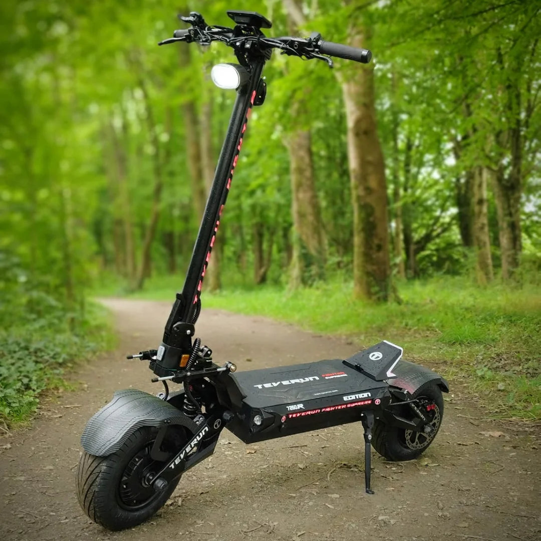 Električni skiro Teverun Fighter Supreme 7260r parkiran na gozdni poti, obdani z zelenjem.