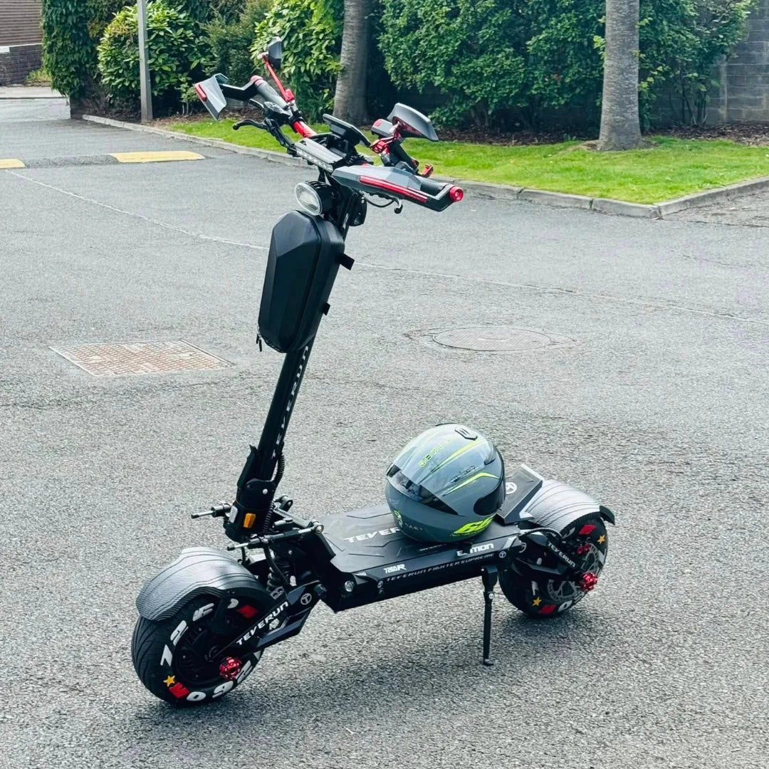 Električni skiro Teverun Fighter Supreme 7260r parkiran na tlakovani površini s čelado v bližini.