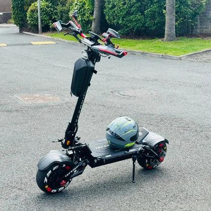 Električni skiro Teverun Fighter Supreme 7260r parkiran na tlakovani površini s čelado v bližini.