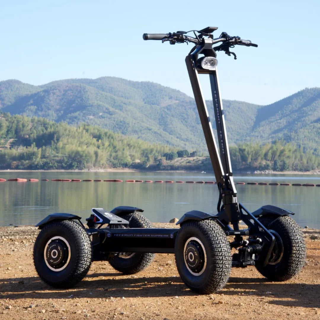 Električni skiro Teverun Tetra 4x4 parkiran ob jezeru z gorami v ozadju.