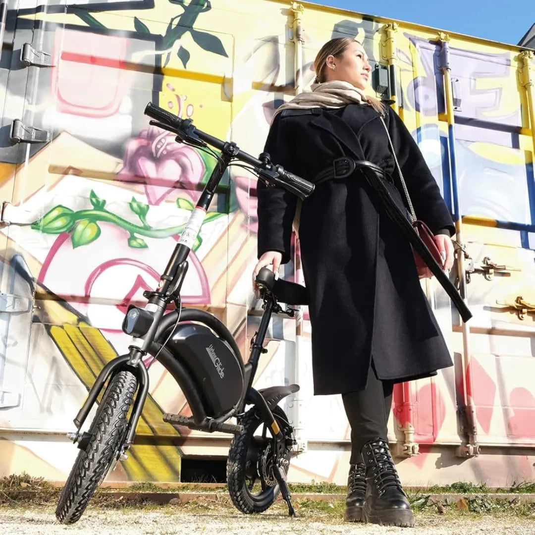 Ženska stoji ob električnem kolesu Urbanglide 160 pred pisano steno z grafiti.
