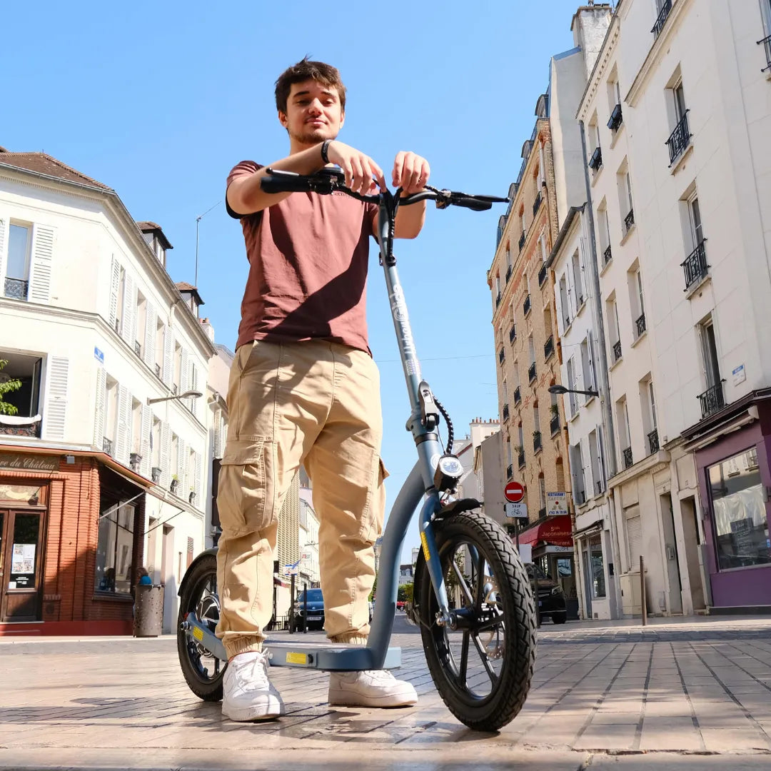 Oseba stoji na električnem skiroju Urbanride 160 City na sončni mestni ulici.