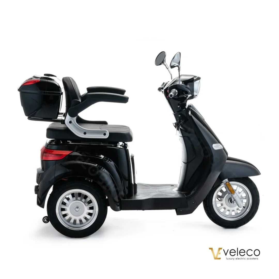Izdelek je električni skuter, znamke Veleco, model Cristal. Na sliki je prikazan skuter v črni barvi, ki ima udobno sedežno površino in prostoren prtljažnik na zadnji strani. Opremljen je z dvema ogledaloma in ima široke kolesa, kar zagotavlja stabilnost med vožnjo.