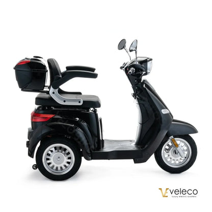 Izdelek je električni skuter, znamke Veleco, model Cristal. Na sliki je prikazan skuter v črni barvi, ki ima udobno sedežno površino in prostoren prtljažnik na zadnji strani. Opremljen je z dvema ogledaloma in ima široke kolesa, kar zagotavlja stabilnost med vožnjo.
