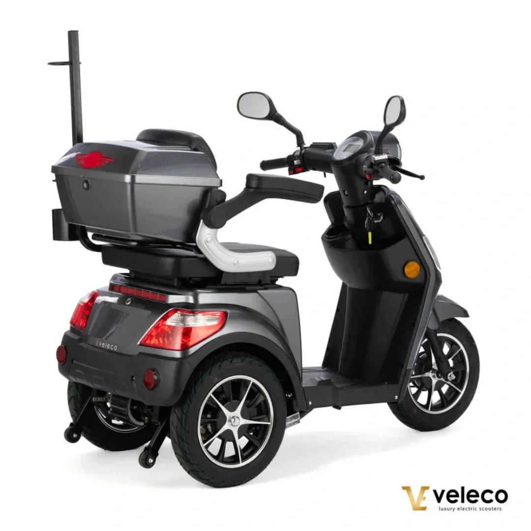 Izdelek je električni skuter, model Veleco Draco. Na sliki je prikazan skuter v temni barvi, ki ima udobno sedežno mesto in prostoren zadnji predal za shranjevanje. Vidne so tudi krmilo, ogledali in kolesa z modernim dizajnom. Skuter je zasnovan za udobno vožnjo in enostavno upravljanje.