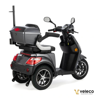 Izdelek je električni skuter, model Veleco Draco. Na sliki je prikazan skuter v temni barvi, ki ima udobno sedežno mesto in prostoren zadnji predal za shranjevanje. Vidne so tudi krmilo, ogledali in kolesa z modernim dizajnom. Skuter je zasnovan za udobno vožnjo in enostavno upravljanje.