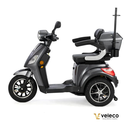 Izdelek na sliki je električni skuter, model Veleco Draco. Skuter ima tri kolesa, kar zagotavlja stabilnost, in je opremljen s širokim sedežem ter prostornim prtljažnikom. Na sprednjem delu so vidne luči in krmilo, kar omogoča enostavno upravljanje. Skuter je zasnovan za udobno vožnjo in je primeren za različne uporabnike.