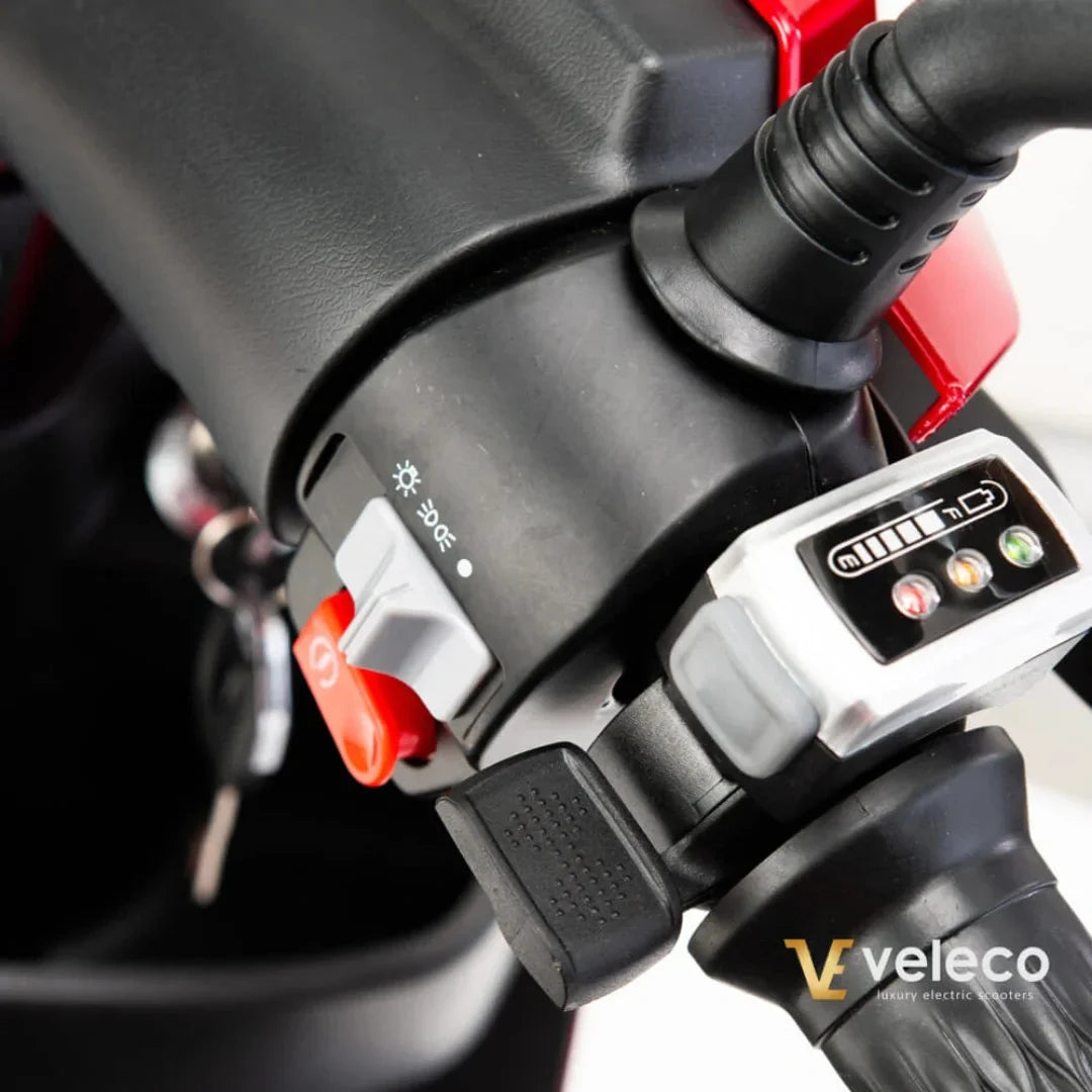 Izdelek na sliki je električni skiro znamke Veleco, model Draco. Vidna je kontrolna plošča, ki vključuje gumb za vklop, stikalo za luči ter indikator stanja baterije. Na ročaju so prikazani tudi različni gumbi in nastavitve, kar nakazuje na funkcionalnost in enostavno upravljanje skiroja.