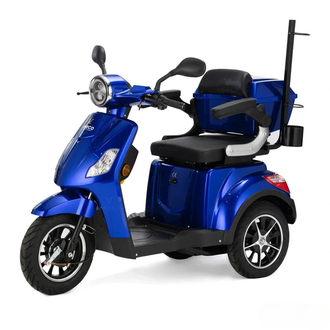 Izdelek je električni skuter, model Veleco Draco. Na sliki je prikazan modri skuter s širokim sedežem in naslonjalom, kar omogoča udobno vožnjo. Ima sprednje luči in krmilo z ročicami, ter prostoren prostor za shranjevanje zadaj. Kolesa so široka, kar zagotavlja stabilnost pri vožnji.