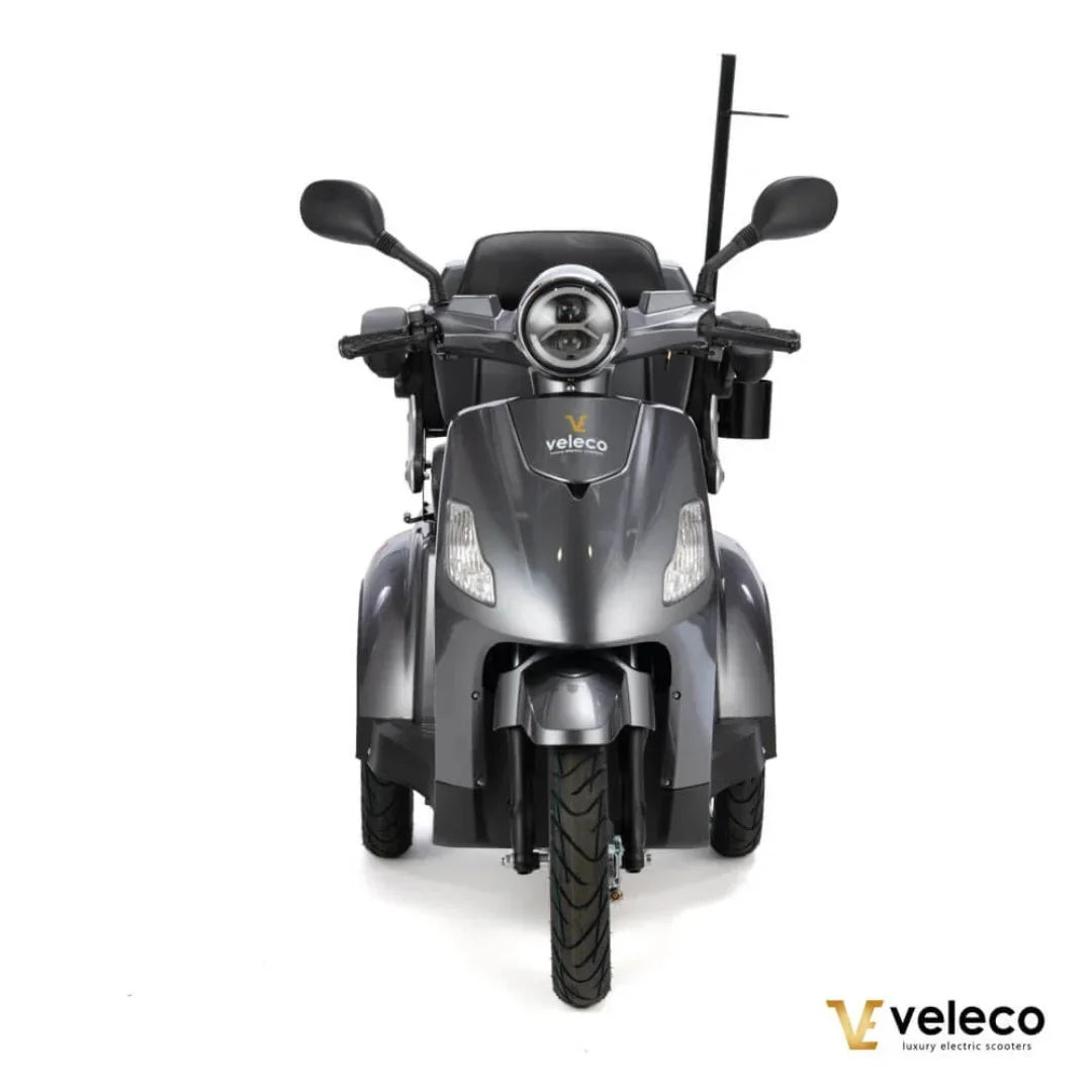 Izdelek je električni skuter, znamke Veleco, model Draco. Na sliki je prikazana sprednja stran skuterja, ki ima moder in eleganten dizajn. Opremljen je z dvema svetlobama na sprednjem delu ter širokimi krmili, kar omogoča udobno vožnjo. Skuter ima tudi široke pnevmatike, kar povečuje stabilnost in varnost med vožnjo.