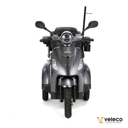 Izdelek je električni skuter, znamke Veleco, model Draco. Na sliki je prikazana sprednja stran skuterja, ki ima moder in eleganten dizajn. Opremljen je z dvema svetlobama na sprednjem delu ter širokimi krmili, kar omogoča udobno vožnjo. Skuter ima tudi široke pnevmatike, kar povečuje stabilnost in varnost med vožnjo.