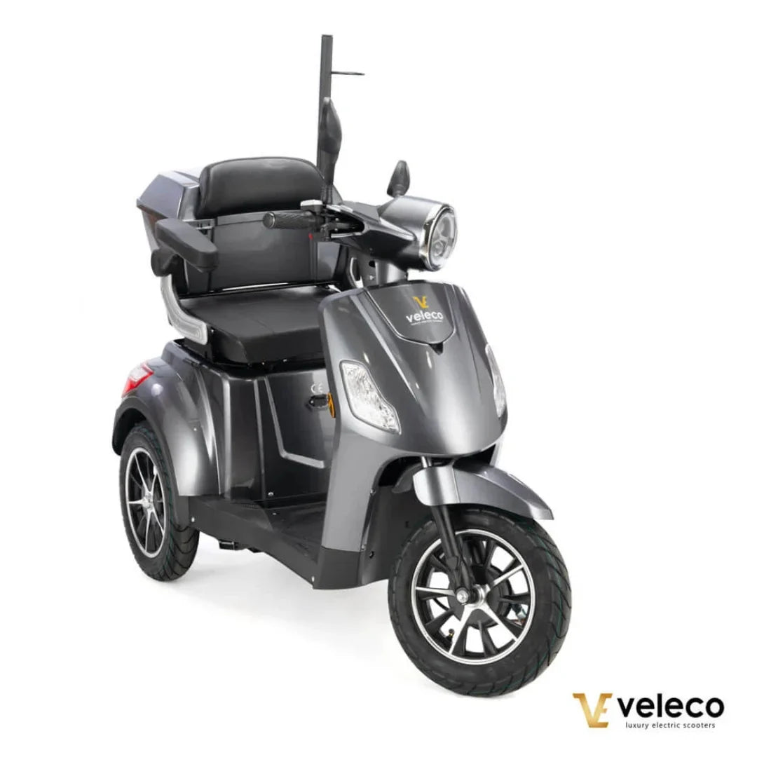 Izdelek na sliki je električni skuter, model Veleco Draco. Skuter ima tri kolesa, kar zagotavlja stabilnost, in je zasnovan za udobno vožnjo. Na sliki je vidno udobno sedežno mesto s hrbtno oporo, prednja luč in krmilo, kar nakazuje na enostavno upravljanje. Zasnova je moderna in elegantna, kar prispeva k njegovemu luksuznemu videzu.