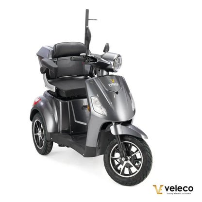 Izdelek na sliki je električni skuter, model Veleco Draco. Skuter ima tri kolesa, kar zagotavlja stabilnost, in je zasnovan za udobno vožnjo. Na sliki je vidno udobno sedežno mesto s hrbtno oporo, prednja luč in krmilo, kar nakazuje na enostavno upravljanje. Zasnova je moderna in elegantna, kar prispeva k njegovemu luksuznemu videzu.