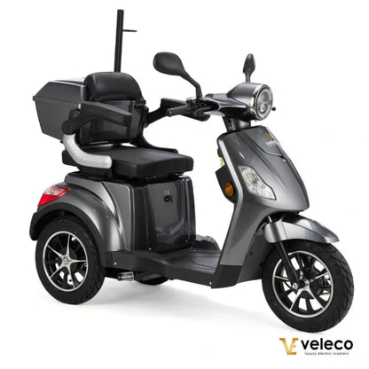 Izdelek na sliki je električni skuter, model Veleco Draco. Skuter ima tri kolesa, kar omogoča stabilno vožnjo, in je opremljen z udobnim sedežem ter prostorom za shranjevanje. Barva skuterja je siva, kar mu daje sodoben videz. Na sprednjem delu je vidna luč in krmilo, kar nakazuje na njegovo uporabnost v urbanem okolju.